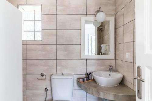 W łazience znajduje się umywalka i lustro. w obiekcie Milia Beach Apartments w mieście Paralia Milia