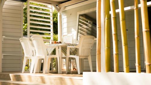 a group of white chairs and a table on a porch at Camping Eden Glamping in Dormelletto