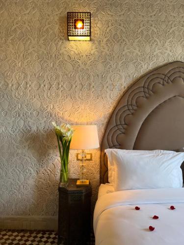 a bedroom with a bed and a lamp with a flower arrangement at Dar Tazi - Medina View in Fès