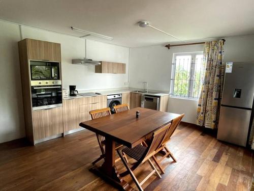 a kitchen with a wooden table and a refrigerator at 2 bedroom Condo -Villa Ibiza in Trou dʼ Eau Douce