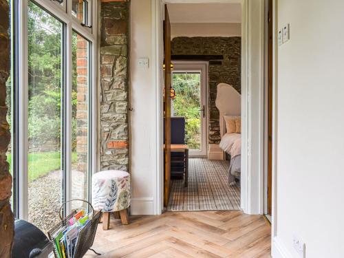 a hallway with a door open to a room with a stone wall at Pigaway Cottage in Petrockstow