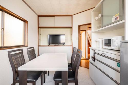 a kitchen with a white table and chairs in a room at 世界遺産と東武日光駅に近い 全内装 3階まで階段あり 駐車場 子供不可 in Nikko