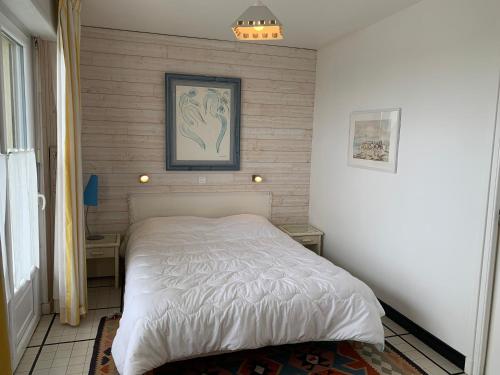- une chambre dotée d'un lit blanc avec une photo sur le mur dans l'établissement Appt de 6 pers - Vu mer proche centre-ville, à Le Touquet-Paris-Plage