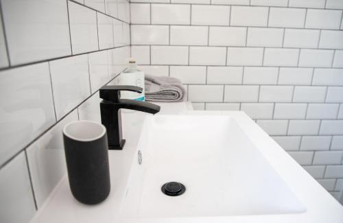a white bathroom sink with a black faucet at Withnell Stays - Apartment Four - Ground Floor in Blackpool