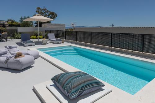a swimming pool with two chaise lounge chairs next to a building at Erolidae Villas in Atsoupádhes
