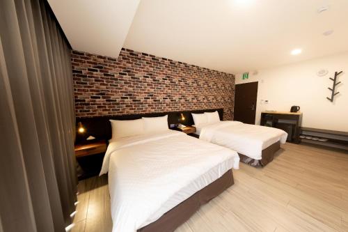 a bedroom with two beds and a brick wall at Only Love Motel in Xindian