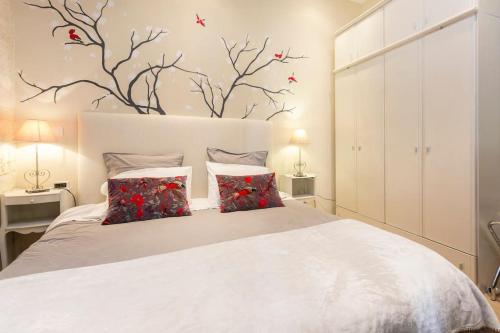 um quarto com uma cama branca com flores vermelhas na parede em Typical 18th century flat, historical center em Avignon
