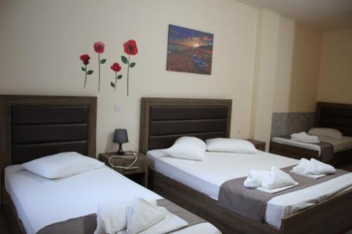 two beds in a room with red flowers on the wall at House Stamatis in Sarti