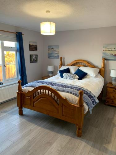 Un dormitorio con una gran cama de madera con almohadas azules en Moneydarragh Cottage with uninterrupted mountain and sea views- Hot tub available for hire, en Annalong