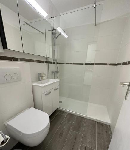 a white bathroom with a toilet and a shower at Meerglück in Burgtiefe auf Fehmarn 