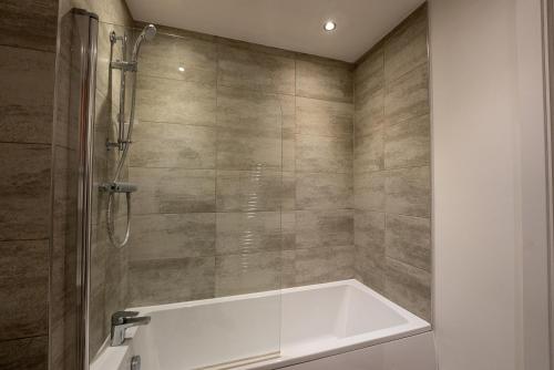 uma casa de banho com banheira e chuveiro em Newly Built Spacious Apartment easily accessible to Luton Airport, Town centre and station em Luton