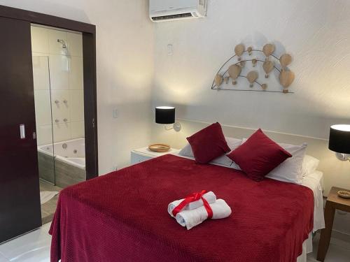 a bedroom with a red bed with towels on it at Pousada 3 Bacias in Penedo