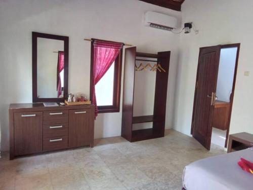 een slaapkamer met een bed, een dressoir en een spiegel bij Gili Air Santay Bungalows in Gili Air