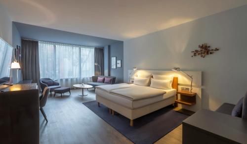 Clayton Hotel Düsseldorf City Centre في دوسلدورف: غرفة نوم مع سرير وغرفة معيشة