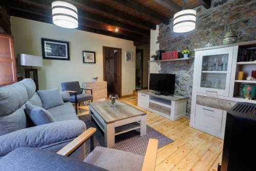 a living room with a blue couch and a tv at Hotel Rural El Molino in Soto de Cangas