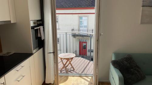 a kitchen with a door open to a balcony with a stool at BERG & BERG APARTMENTS - Spiez Self-Check-in in Spiez