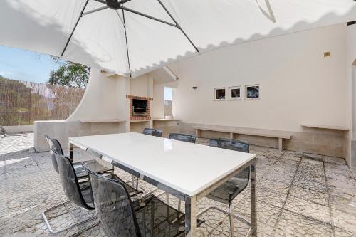 a white table and chairs with an umbrella at Soltroia Beach Court -Heated Pool in Troia