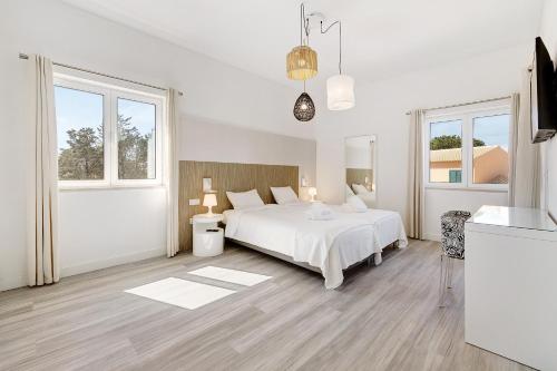 Dormitorio blanco con cama blanca y ventanas en Soltroia Beach Court Villa, en Tróia