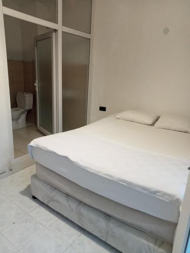 a white bed in a room with a bathroom at Modestus pansiyon otel in Usak