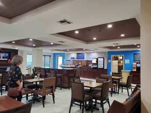 a person standing in a restaurant with tables and chairs at Holiday Inn Express & Suites San Antonio West Sea World Area by IHG in San Antonio
