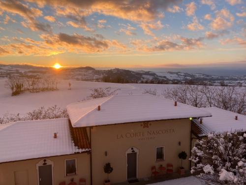 a building covered in snow with the sunset in the background at La Corte Nascosta Volpedo in Volpedo
