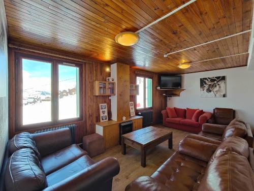 ein Wohnzimmer mit Ledersofas und einem Tisch in der Unterkunft Le Petit Mont Blanc in Peisey-Nancroix