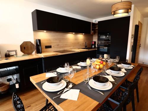 - une grande table en bois avec des assiettes et des verres à vin dans l'établissement Superbe Appartement 4 Étoiles, 2 Chambres, Proche Pistes, Balcon, Parking, Ski & Vélo - FR-1-623-329, aux Gets