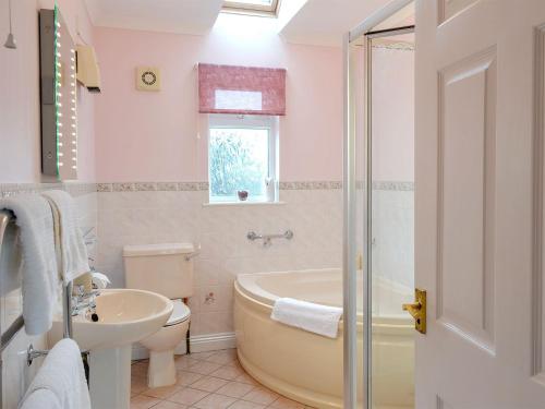 a bathroom with a tub and a toilet and a sink at Little Coombe in Ashbury