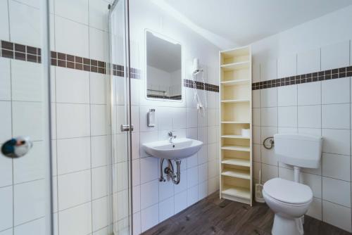 a white bathroom with a toilet and a sink at Aparthotel Stralsund Studios und Apartments in Stralsund