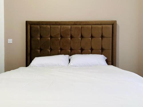 a large bed with white sheets and a brown headboard at Marina Apartments in Bradford