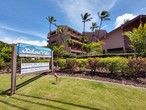 a sign in front of a building with palm trees at Hale Mai Hopohopo in Kahana