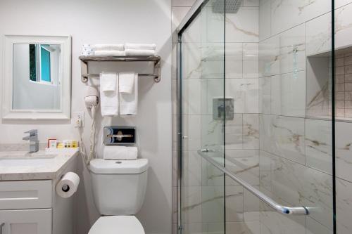 a bathroom with a toilet and a glass shower at Studio City Court Yard Hotel in Los Angeles