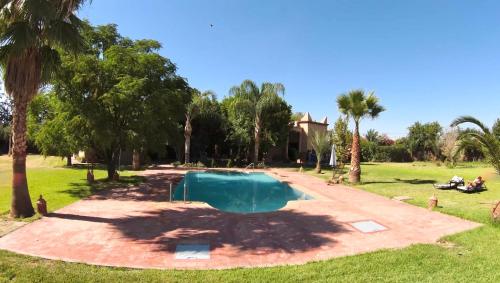 - une piscine dans une cour avec des palmiers dans l'établissement Teacook Marrakech, à Ouled el guerne