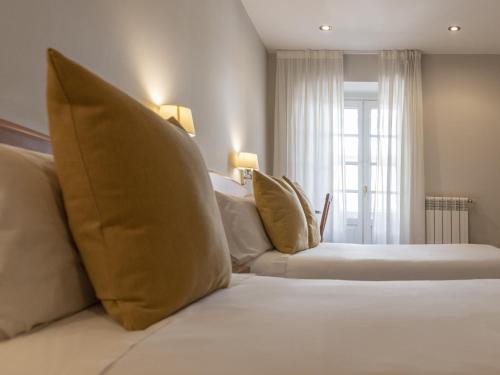 Un dormitorio con una cama blanca con almohadas y una ventana en Hostal ALBA Lugo, en Lugo