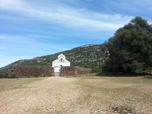 an old brick building with a mountain in the background at B&B Antico Telaio in Santa Maria Navarrese