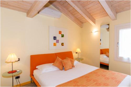a bedroom with a bed with white sheets and an orange headboard at Casa Nova in Burano