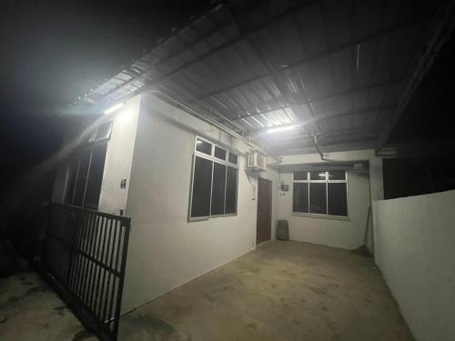 a dark room with a white building with windows at HOMESTAY NO.45 in Jitra