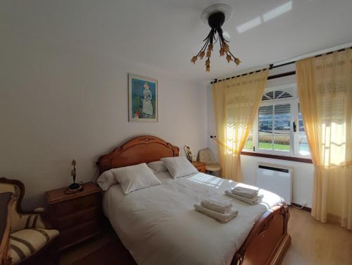 a bedroom with a bed and a chair and a window at Casa Victoria - Laxe in Laxe