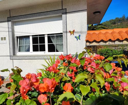 ein Blumenstrauch vor einem Haus mit einem Fenster in der Unterkunft Casa Victoria - Laxe in Laxe