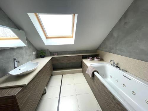 ein Badezimmer mit einer Badewanne, einem Waschbecken und einem Dachfenster in der Unterkunft Superbe maison Châtillon-Le-Duc 