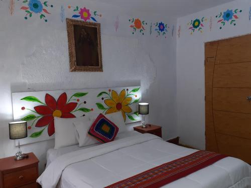 a bedroom with a bed with flowers on the wall at Reinbo Garden in Cusco