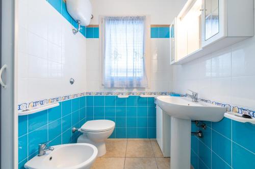 a blue and white bathroom with a toilet and a sink at Sottotorre 1 in Calasetta
