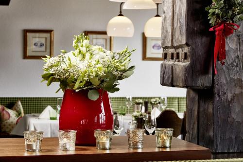 a red vase with white flowers on a table at Hotel Hirlanda in Zürs am Arlberg