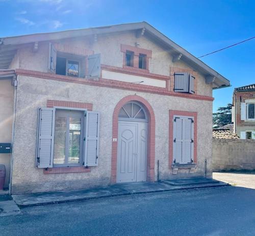 uma casa com uma porta branca e duas janelas em La maison du Maire em Cayrac