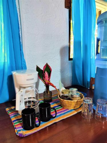 a table with a coffee maker and a basket of cups at Maya Mountain Lodge in San Ignacio