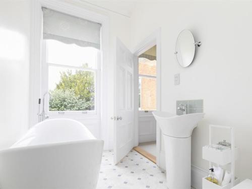 a white bathroom with a tub and a sink at Mount Ephraim B&B in Hernhill
