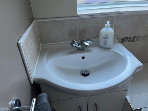 - un lavabo dans la salle de bains avec une bouteille de savon dans l'établissement 2 bed house near Sefton Park & Lark Lane, à Liverpool