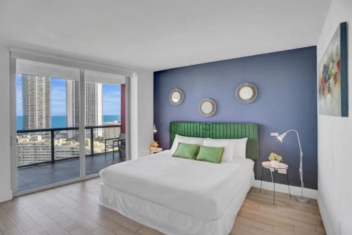 a bedroom with a large white bed and a blue wall at Condo 3 Bedrooms 2 min from the beach in Hallandale Beach