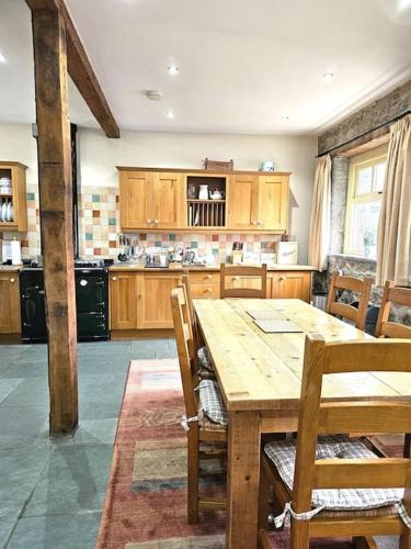 a kitchen with a wooden table and wooden cabinets at Hound Tor Barn Dartmoor in Manaton