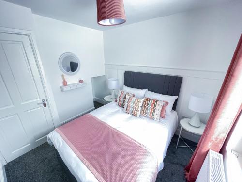 a small bedroom with a bed with a pink blanket at Tettenhall Village Townhouse in Wolverhampton